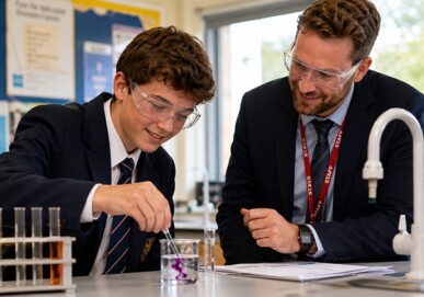 Male student conducting a chemistry experiment with a teacher in a school science laboratory
