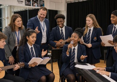Secondary school students performing music with guitars, ukulele and microphone alongside two teachers in a performing arts space